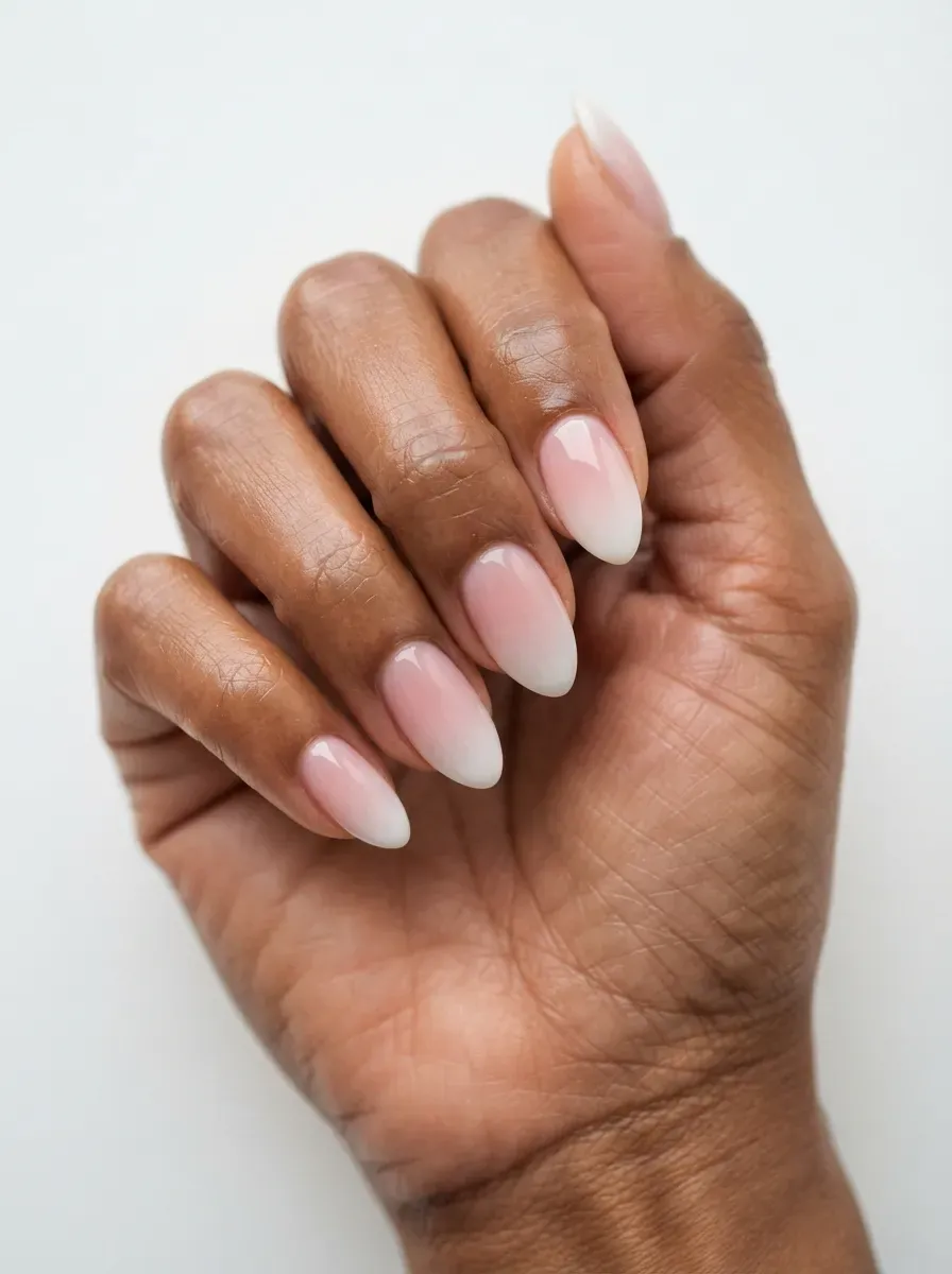 Close up of almond nails with pink base fading softly into milky white tips