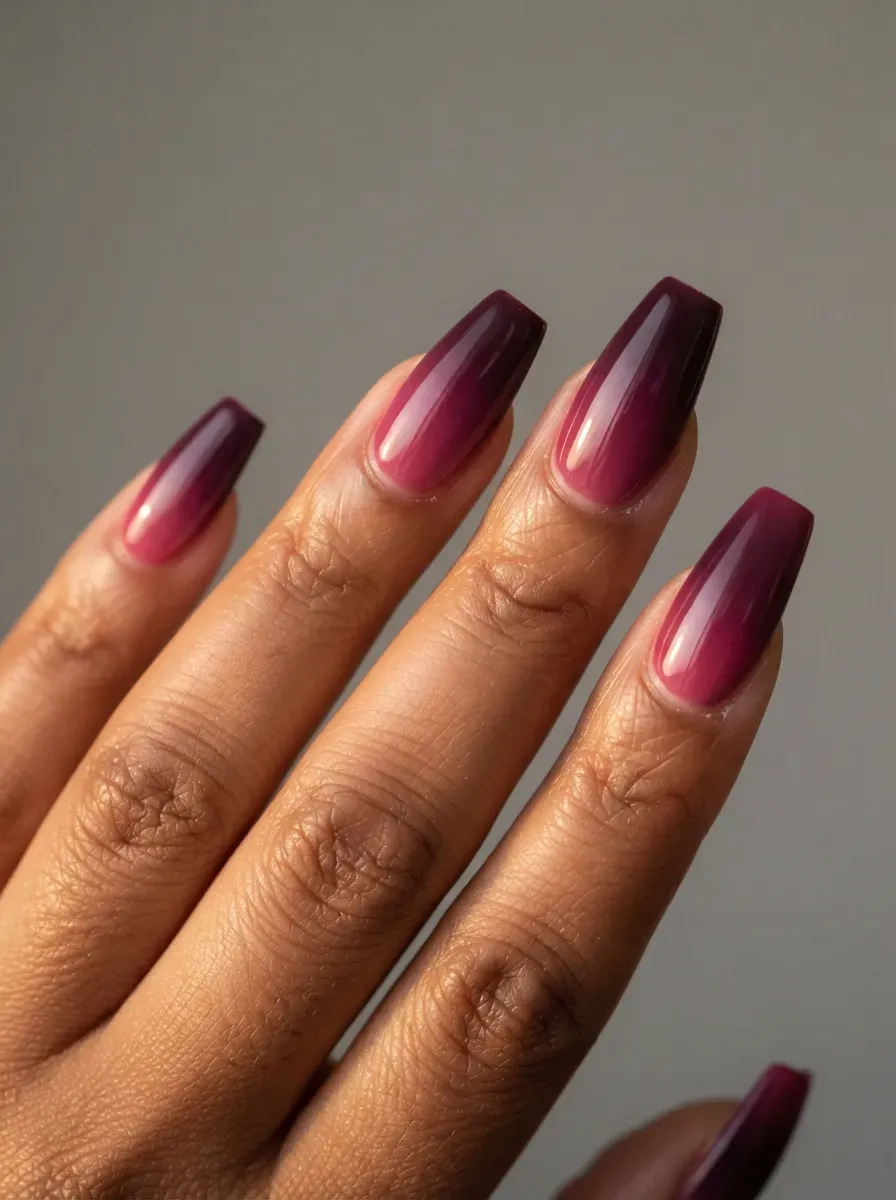 Close-up of long coffin nails with berry ombre blending on deep brown skin