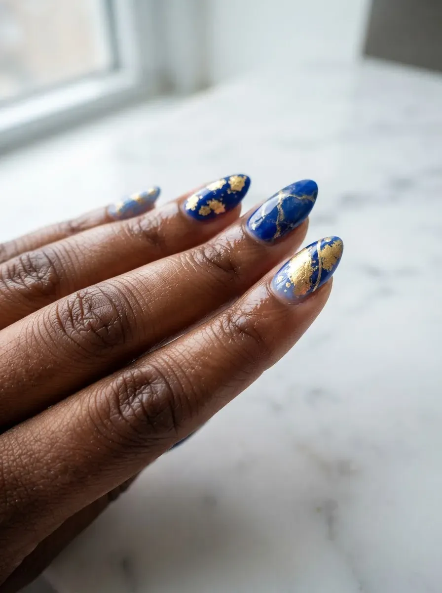 Close-up of nails in blue and gold mixed set on deep chestnut skin