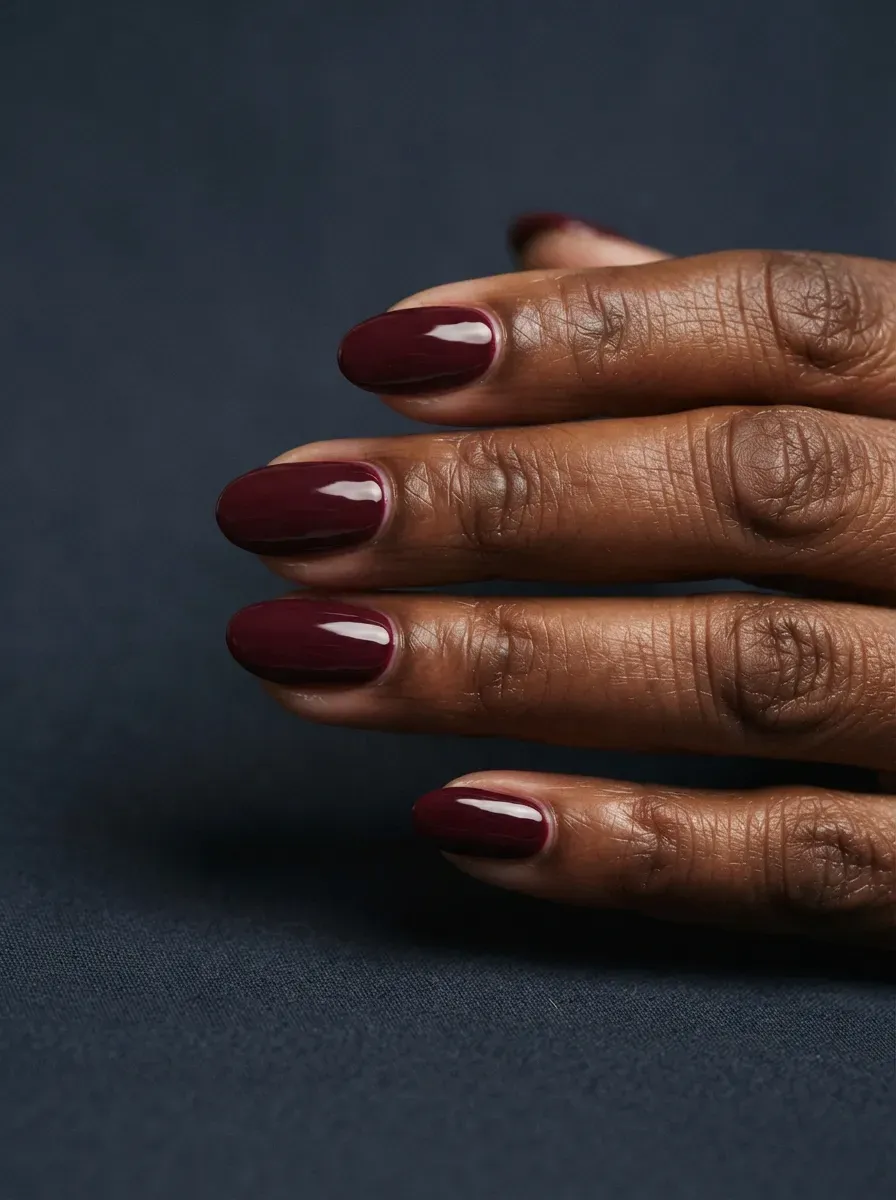 Close up of oval nails in deep burgundy wine polish with glossy finish