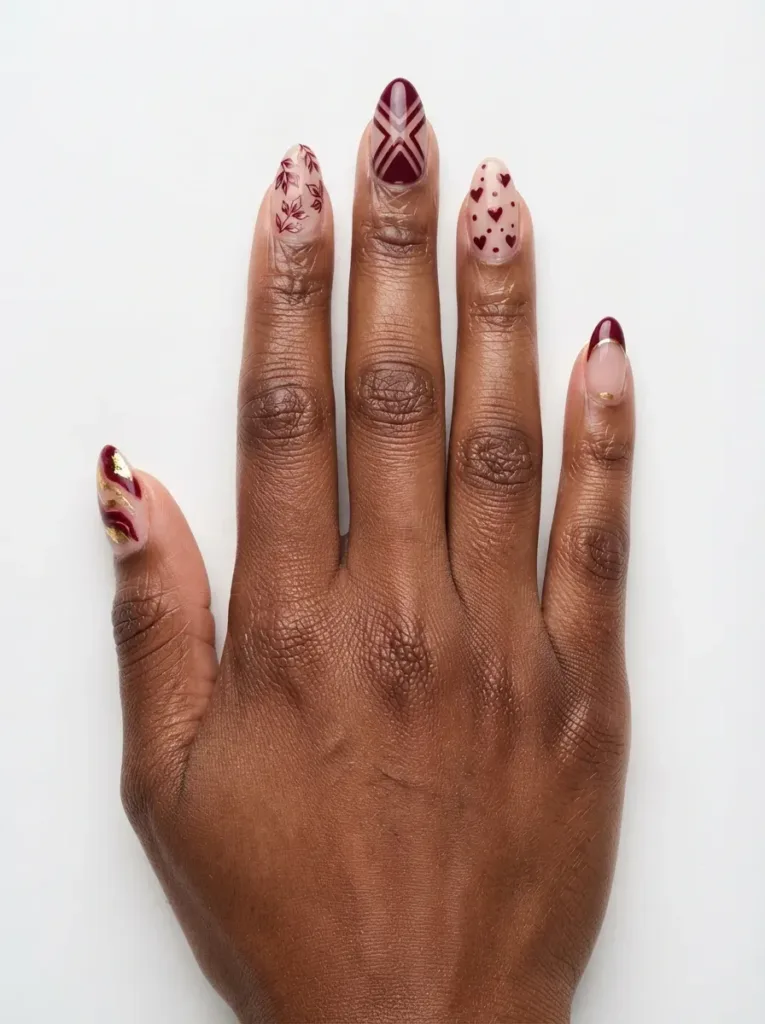 Close-up of almond nails with different art sharing one burgundy color