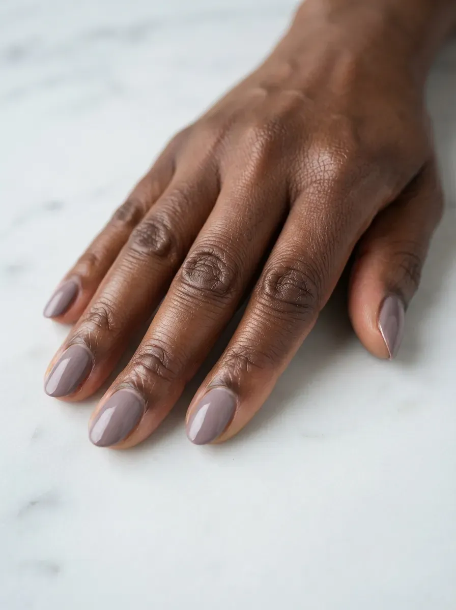 Close up of short almond nails in dusty mauve cream polish with smooth finish