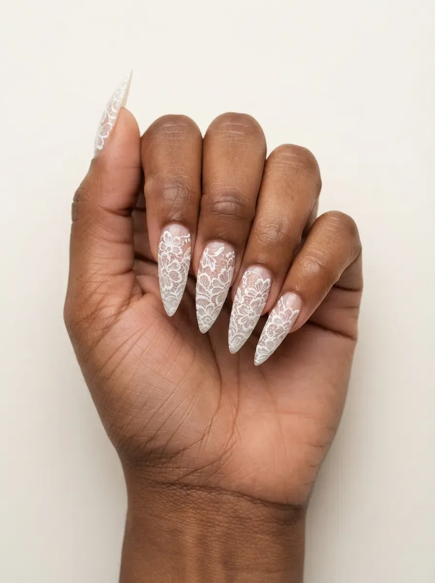 Close-up of long stiletto nails with full white lace over nude on brown skin