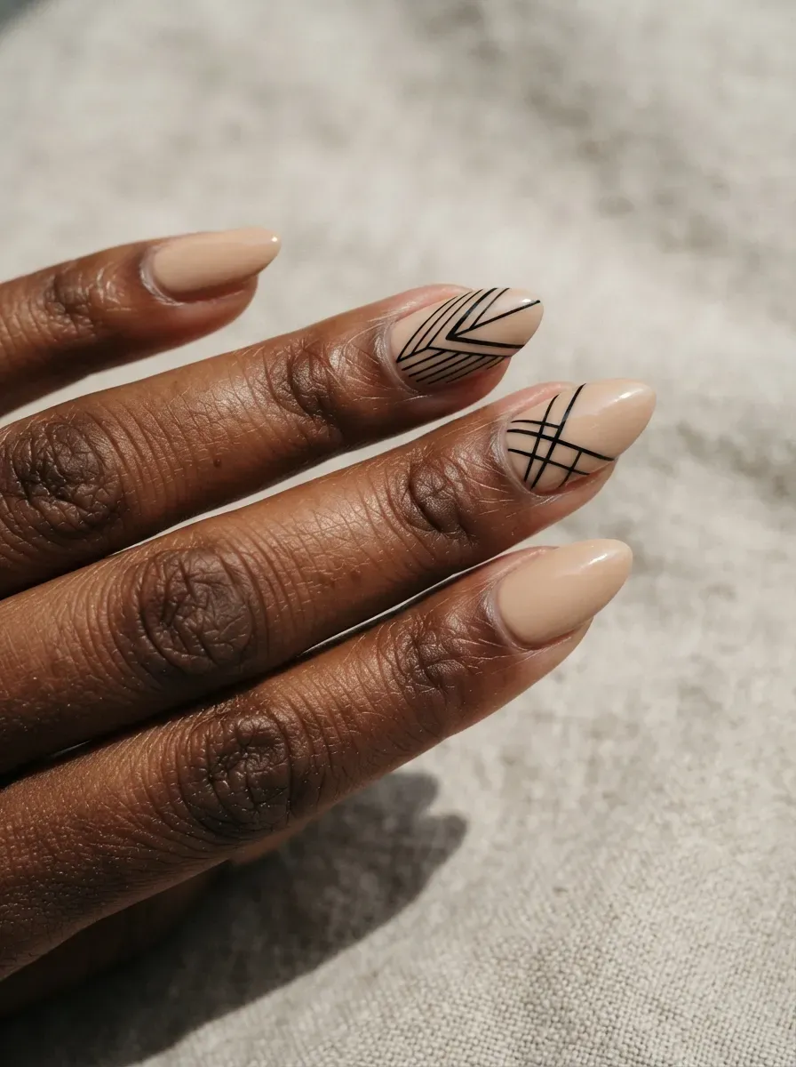 Close-up of almond nails in beige with black geometric line accent nails