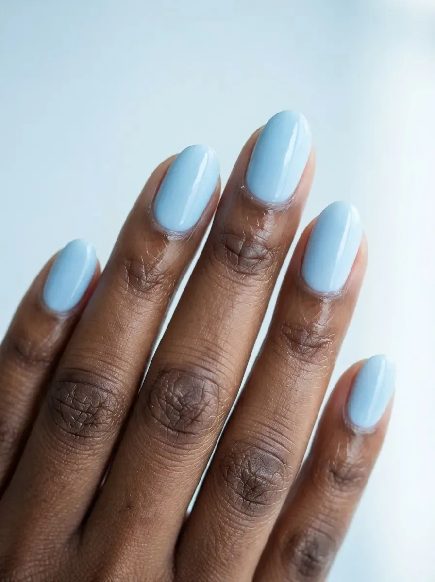 Close-up of oval nails in glossy ice blue on rich dark skin tone