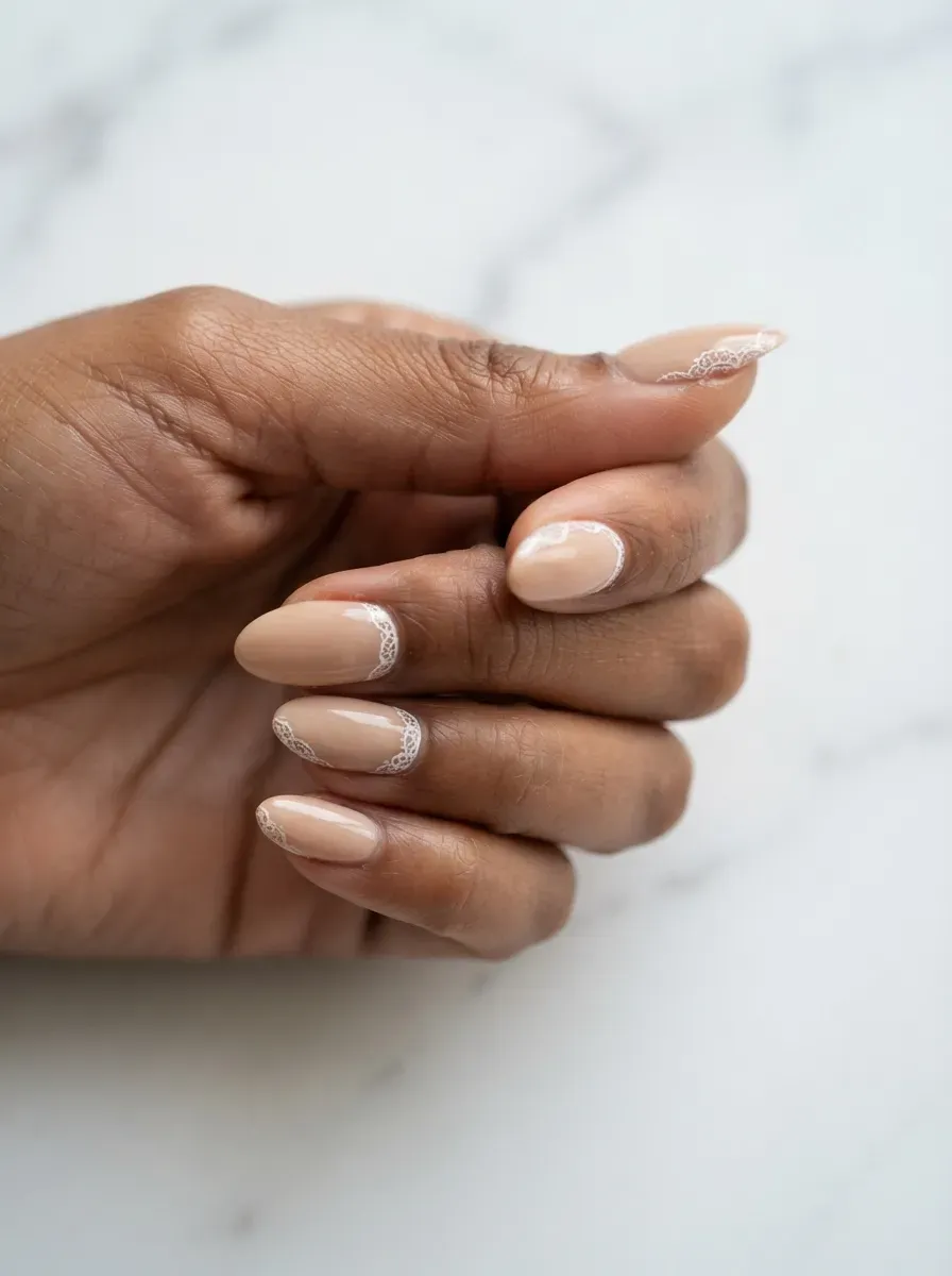 Close-up of almond nails split between white lace and French tips on deep brown skin