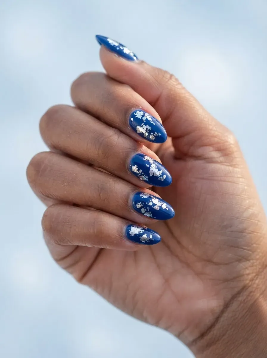 Close-up of blue nails with silver foil for holidays on brown skin and warm undertones