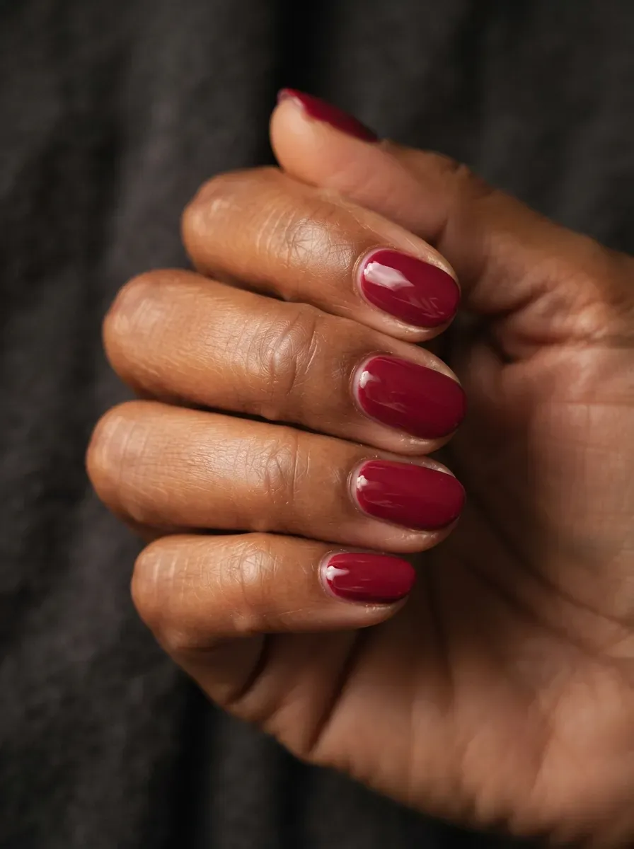 Close up of short oval nails in deep red polish with high gloss festive finish
