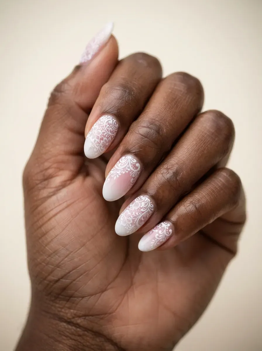 Close-up of almond nails with white lace over baby boomer ombre on deep brown skin