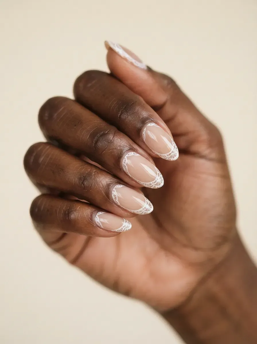 Close-up of almond nails with white lace borders framing sheer centers on rich dark skin