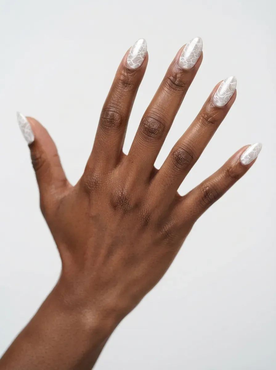 Close-up of almond nails with white lace over soft chrome base on deep chestnut skin