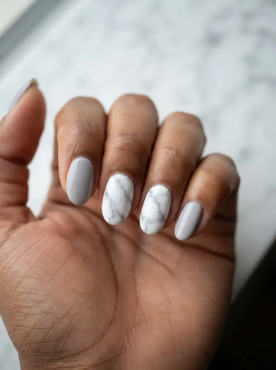 Close-up of oval nails in gray with white marble accent nails