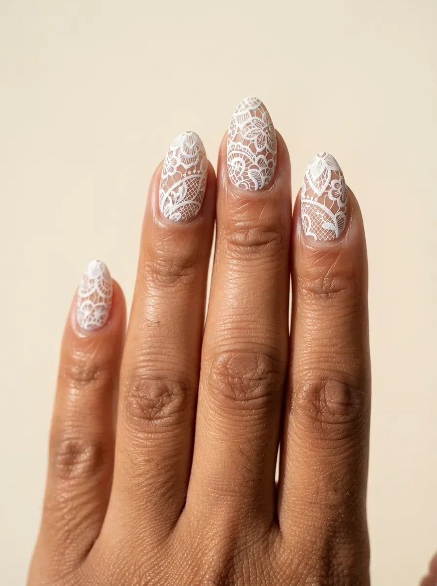 Close-up of almond nails with negative space lace and bare gaps on warm brown skin