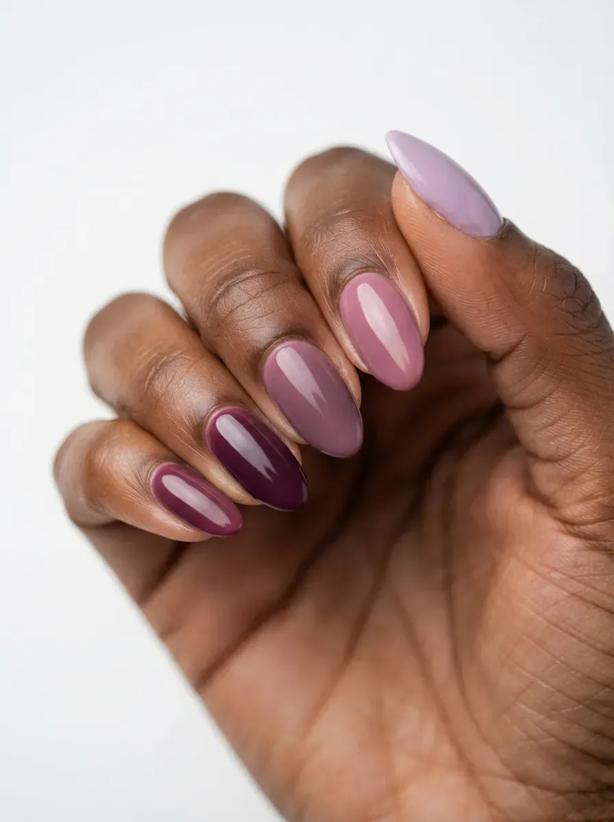 Close-up of almond nails fading from deep plum to pale lavender