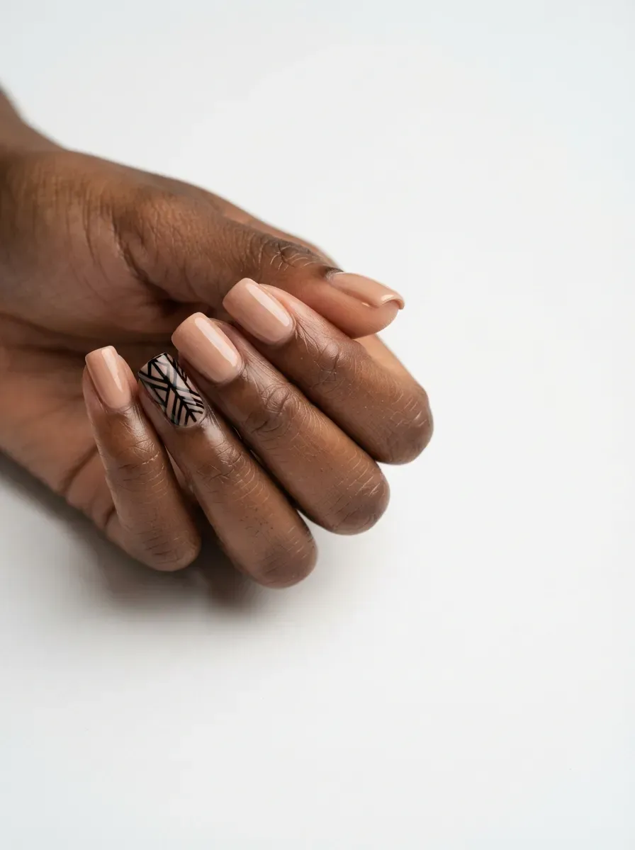 Close-up of square nails in nude with black graphic accent nails