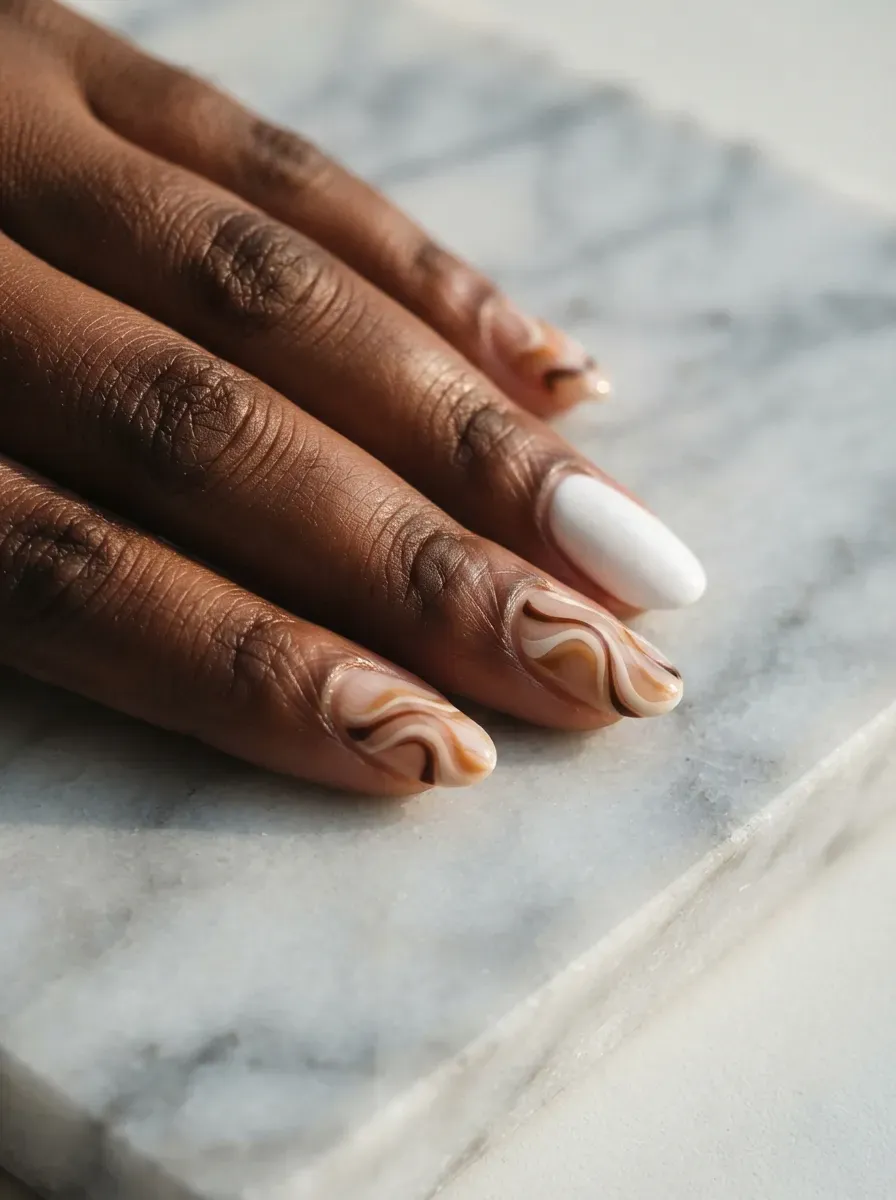 Close-up of oval nails in white with beige brown swirl accent nails