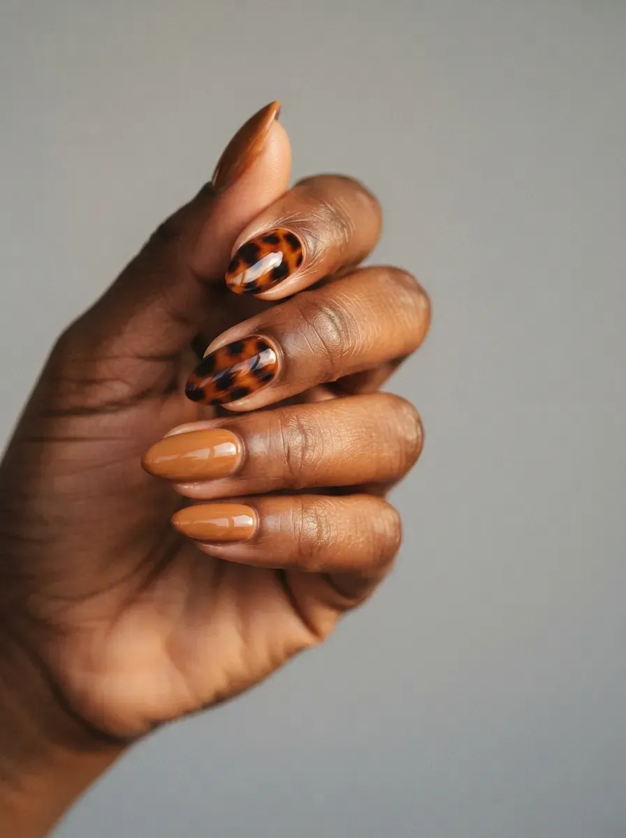 Close-up of almond nails in caramel with tortoiseshell accent nails
