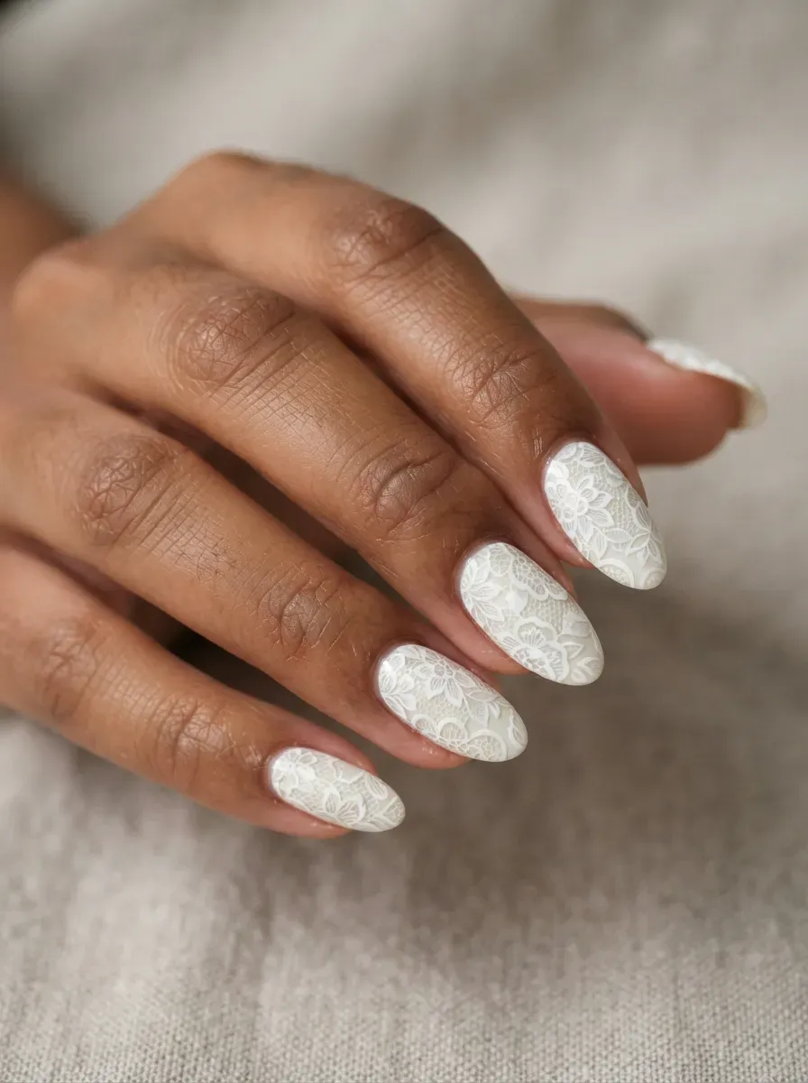 Close-up of almond nails with two-tone lace in white and ivory on warm brown skin