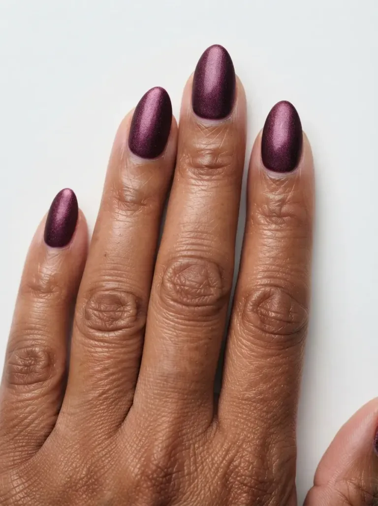Close-up of almond nails with deep plum velvet shimmer on brown skin with warm undertones