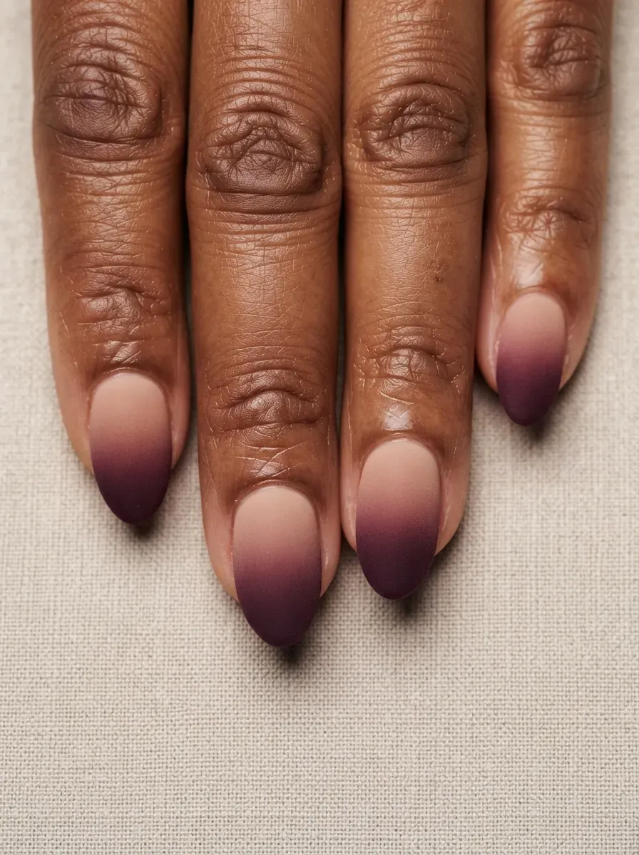 Close-up of velvet ombre nails fading nude to plum on warm brown skin