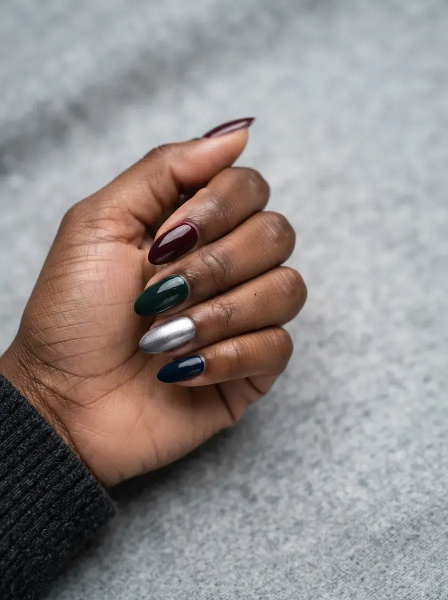 Close-up of almond nails in burgundy forest navy with silver accent
